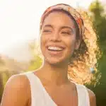 A confident woman with a dazzling, natural smile, representing the beautiful aesthetic results of porcelain veneers.