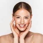 Image of beautiful half-naked woman smiling at camera and touching her face