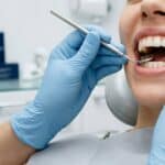 Close-up of a smiling person’s teeth being examined by a dentist using dental tools in a bright, clean examination room Dentistry