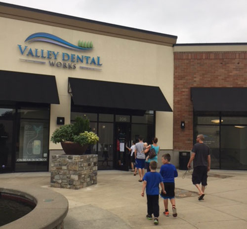 front of dental office with adults and children walking inside